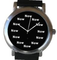 "Now" Is the Time That Is Shown Each Hour on the Black Dial of the Brushed Chrome Round Shape with a Black Leather Strap
