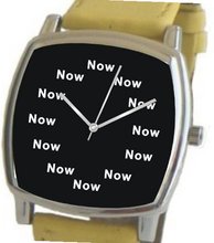 "Now" Is the Time That Is Shown Each Hour on the Black Dial of the Polished Chrome Cushion Shape with a Yellow Leather Strap